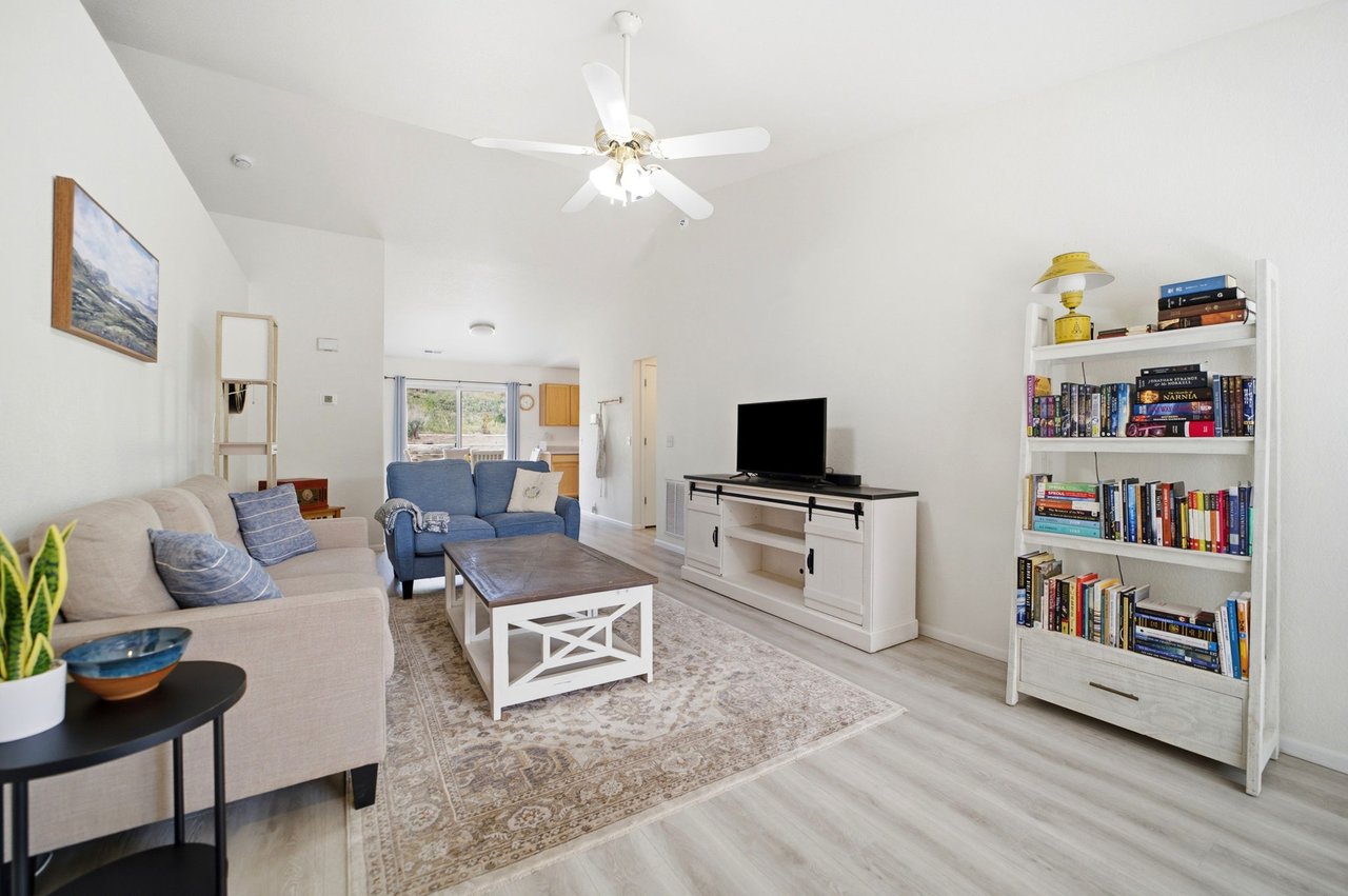 Living room with ceiling fan, vaulted ceiling, and bright open floor plan