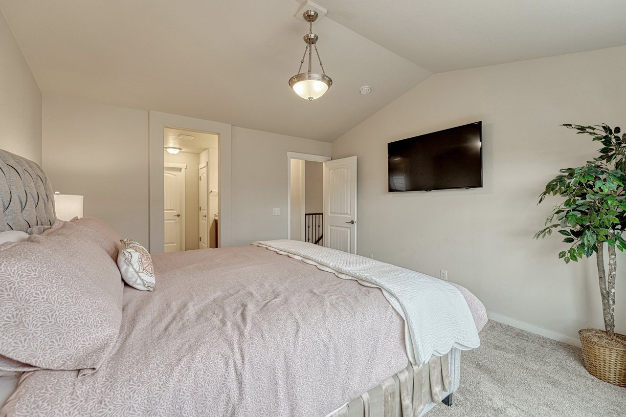 Primary bedroom with vaulted ceiling and doorway to the en-suite bathroom