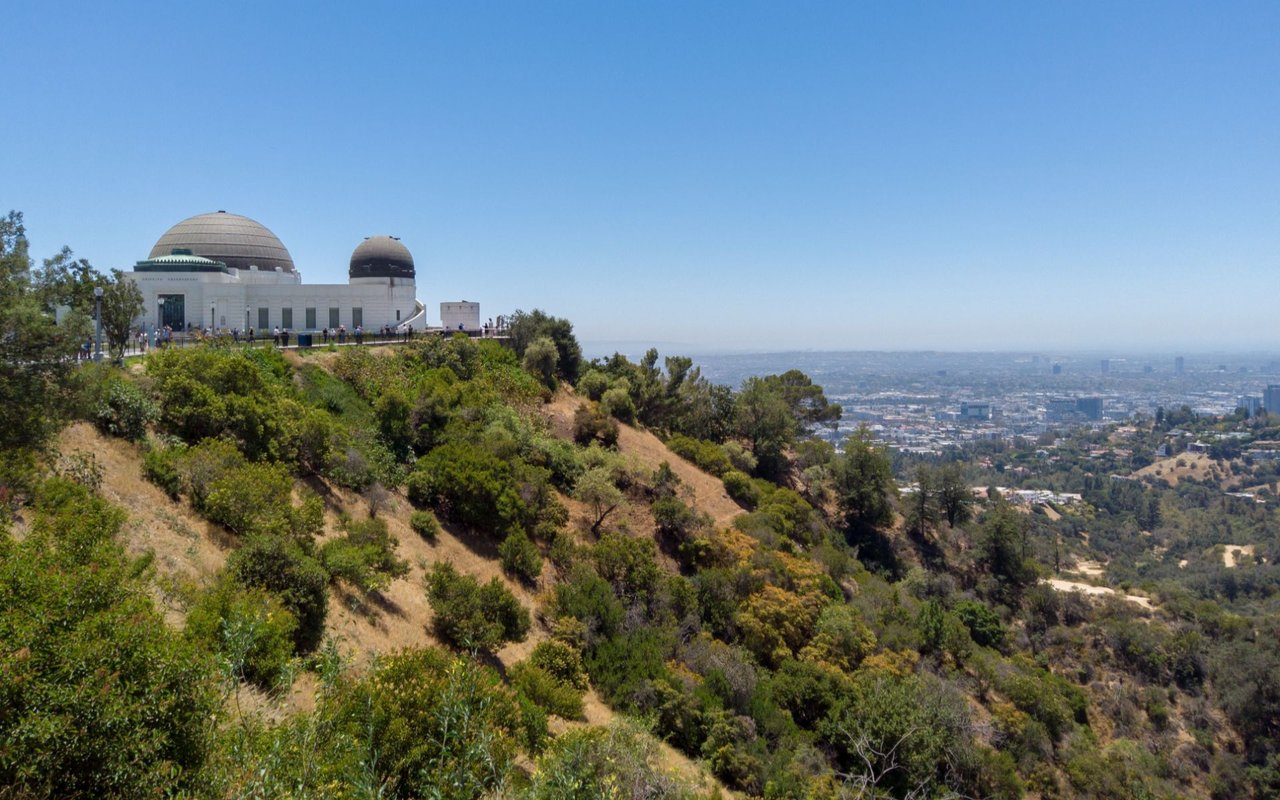 Griffith Observatory overlooks Los Angeles from a brush-covered hillside.