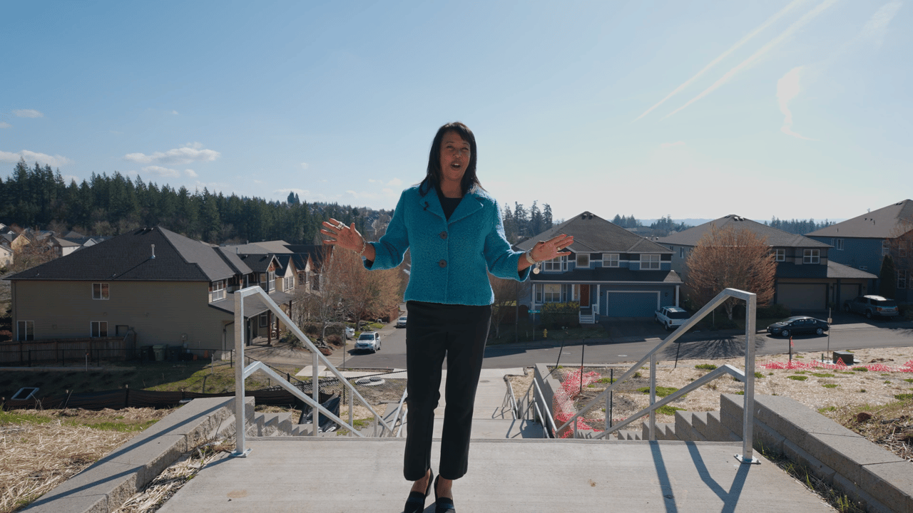 Tamiko Warren stands on a new construction site in Portland, overlooking a residential neighborhood—highlighting the importance of hiring a Realtor when buying new construction homes.