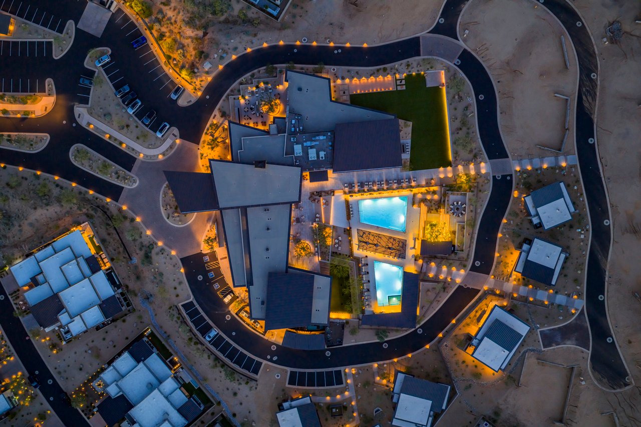 Aerial view of Sereno Canyon’s illuminated clubhouse and two swimming pools at dusk.