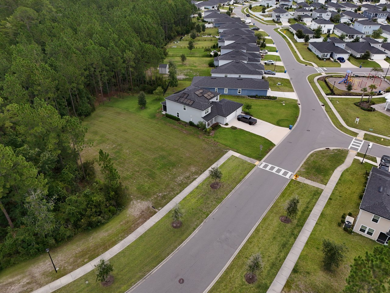 Aerial view of Meadow Ridge homes beside a wooded area, with a playground across the street.