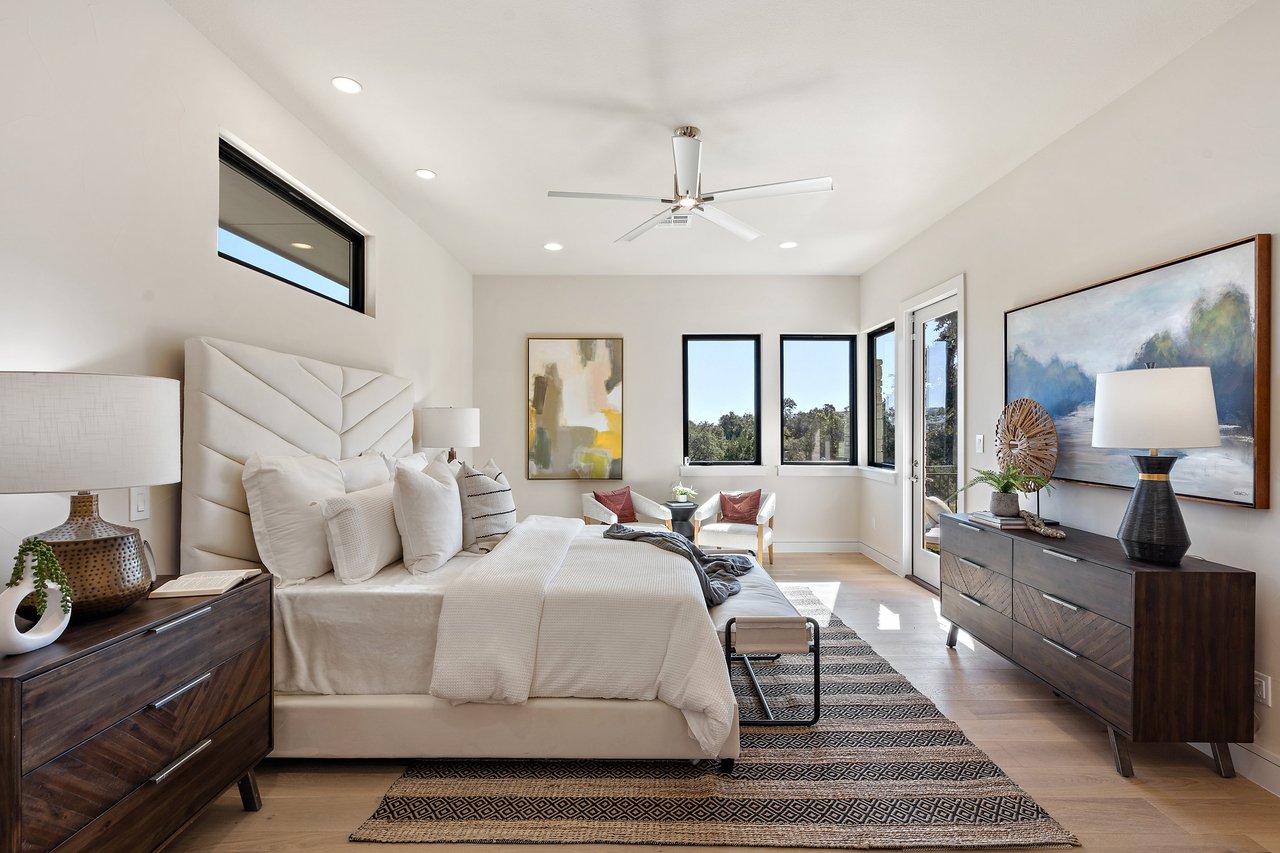 Primary bedroom with an upholstered headboard and natural light at this Caudill Lane home in the Bee Caves area of Austin, Texas.