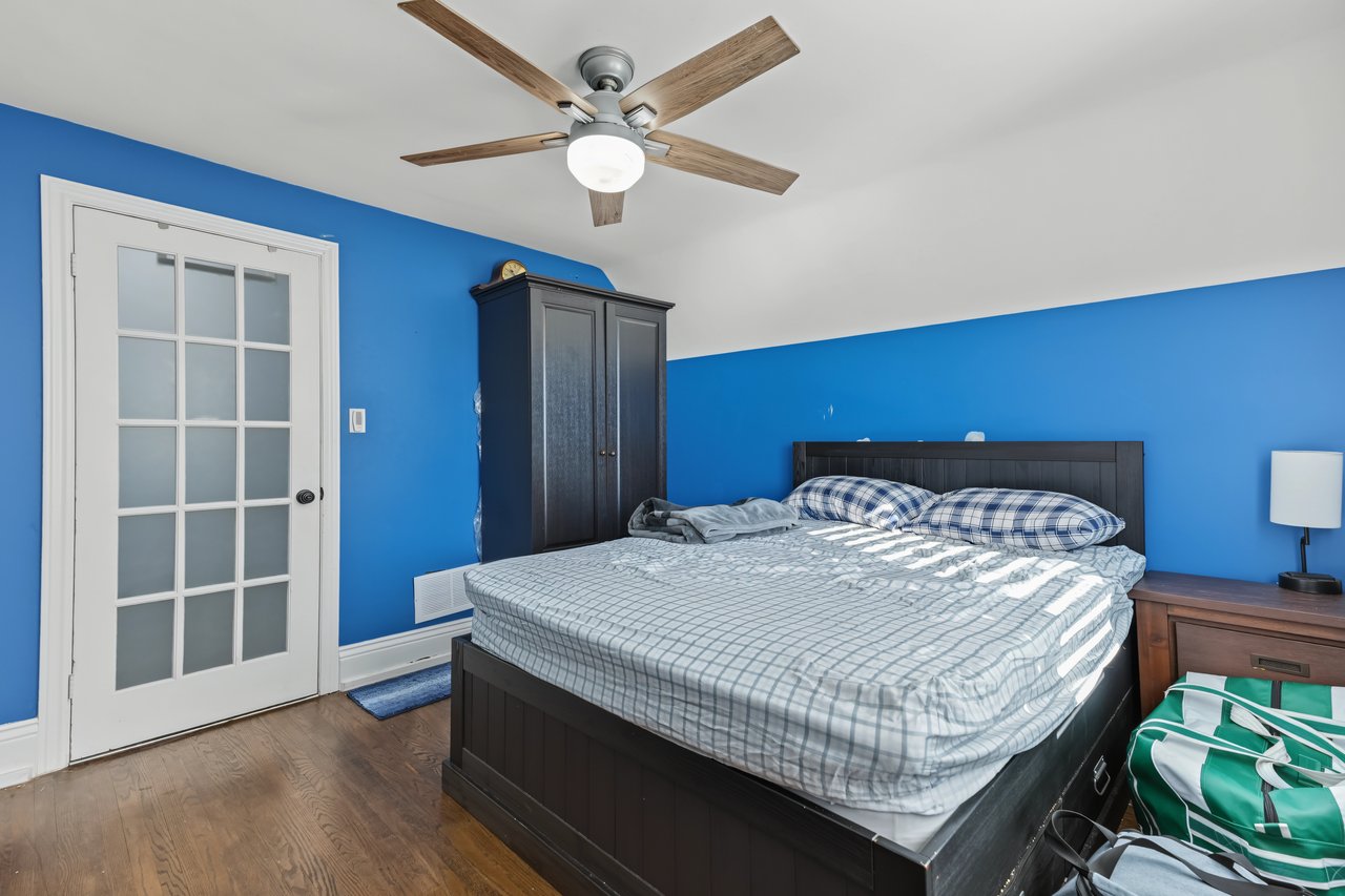 Bedroom with bright blue walls, a dark bed, and a white glass-paneled door.