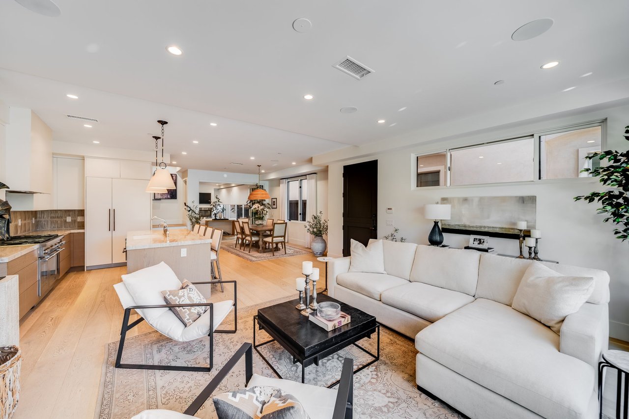 Furnished open-plan living room with a white sectional, dining area, and kitchen.