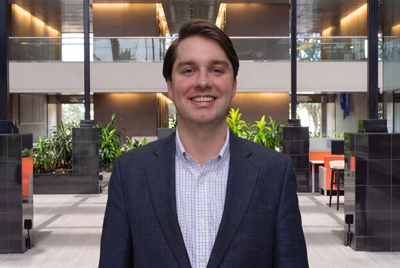 Will Gosnell in a navy blazer and checked shirt in a modern office atrium.