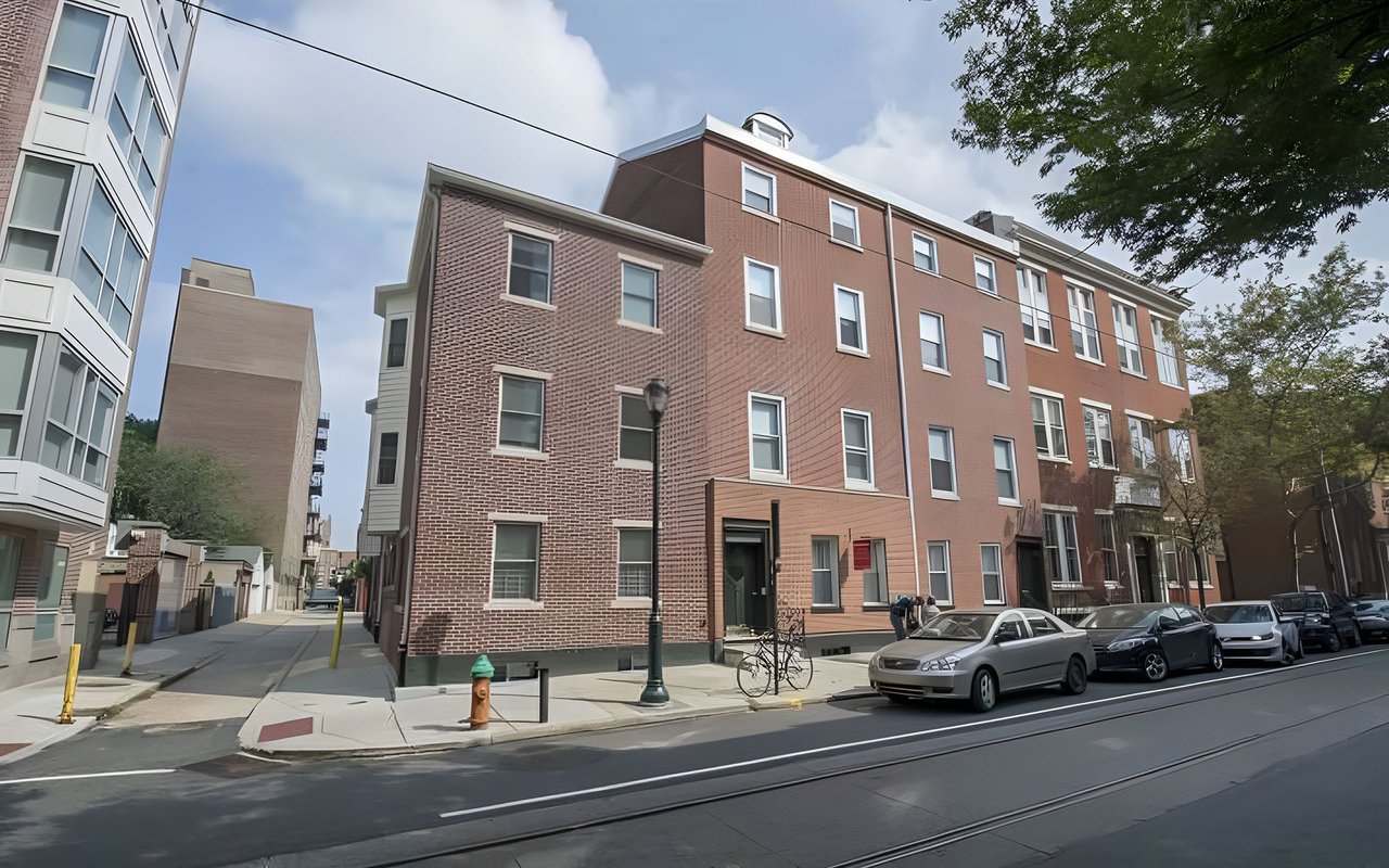 Brick condominium building with white-trimmed windows along a city street.