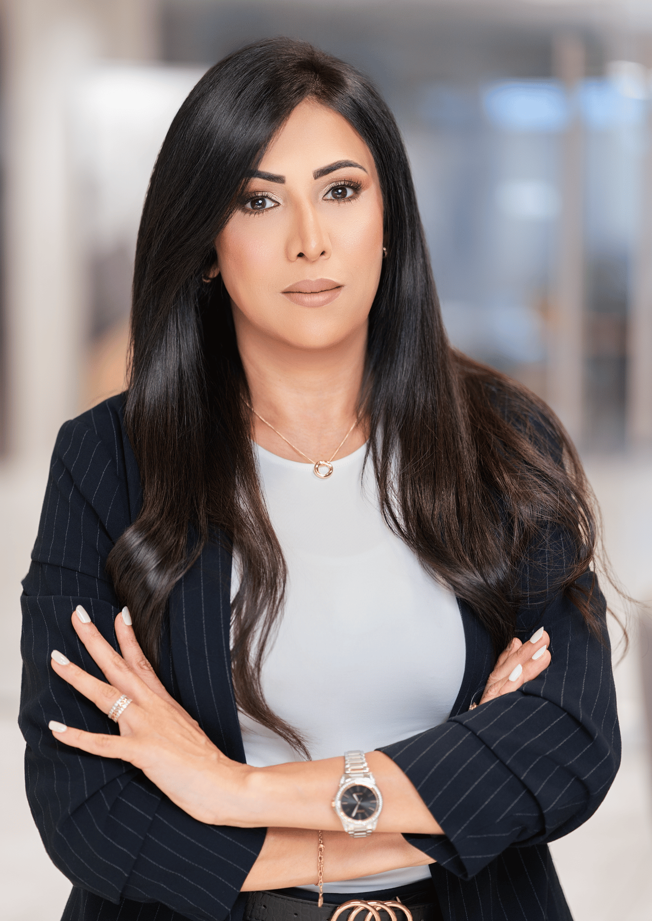 Samar Alqhtany, arms crossed in a navy pinstripe blazer and white top.