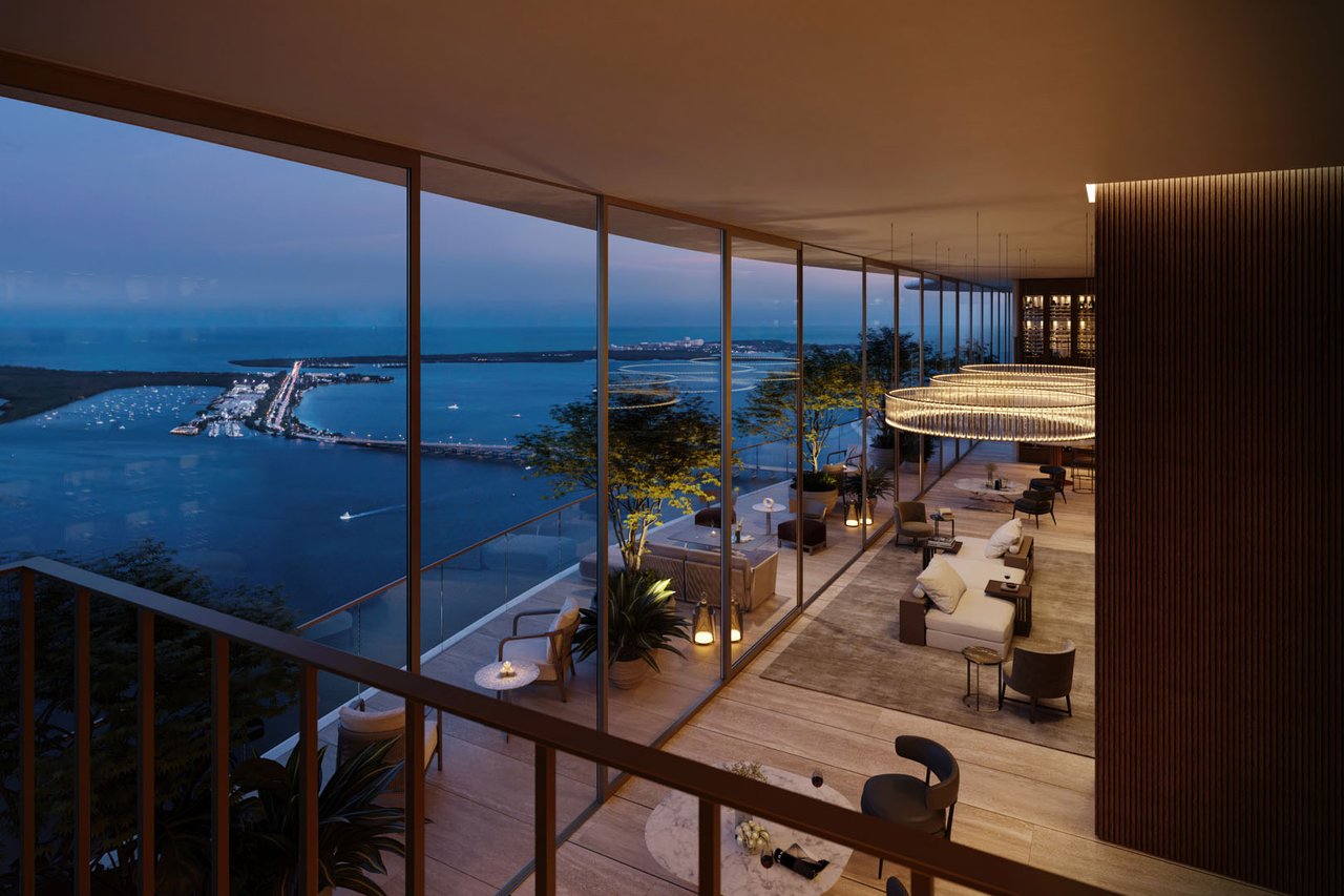High-rise lounge with floor-to-ceiling windows overlooking Biscayne Bay at dusk.