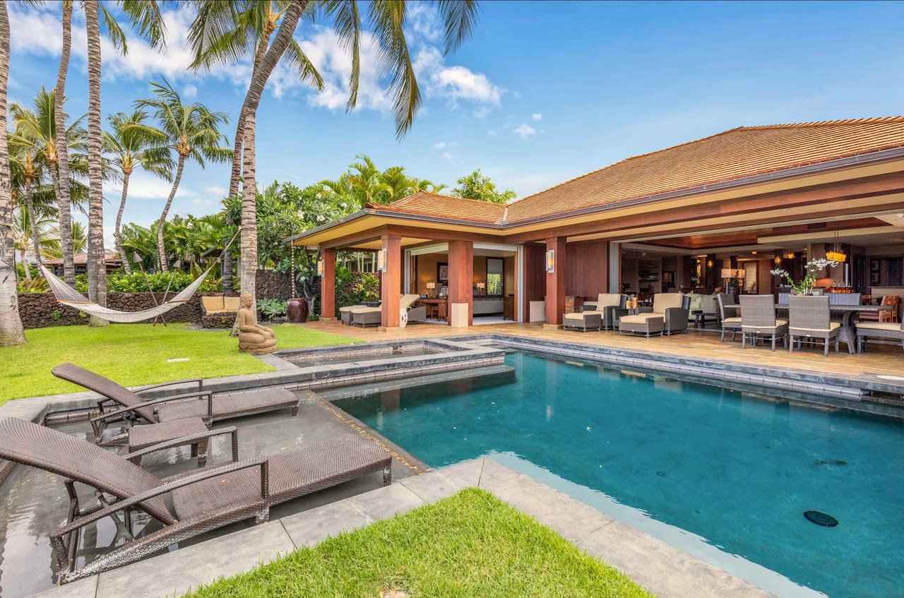 Tropical home beside a pool, with a covered lanai, palm trees, and a hammock.