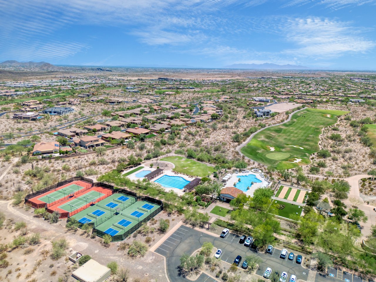 Aerial view of the neighborhood around 30959 North 120th Ave, with a golf course, tennis courts, swimming pools, and homes across the desert landscape.