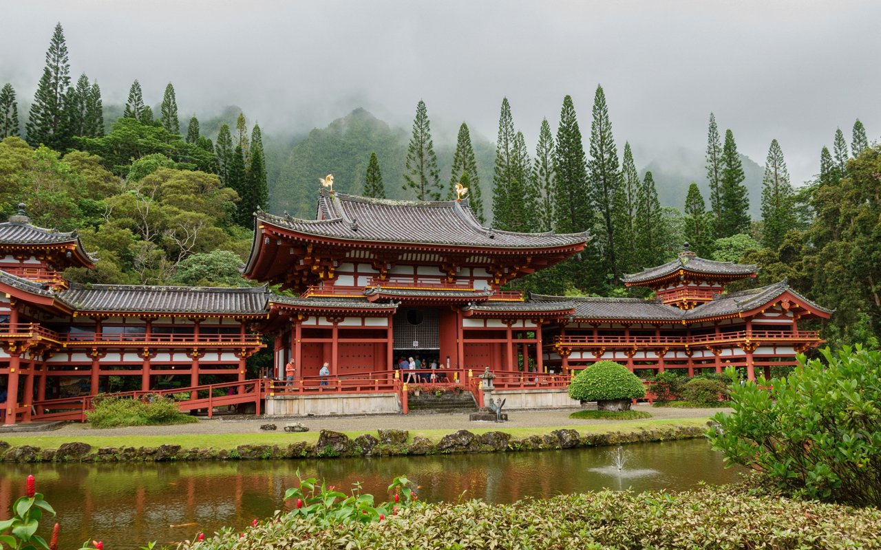 Byodo-In Temple beside a pond, backed by misty green mountains.