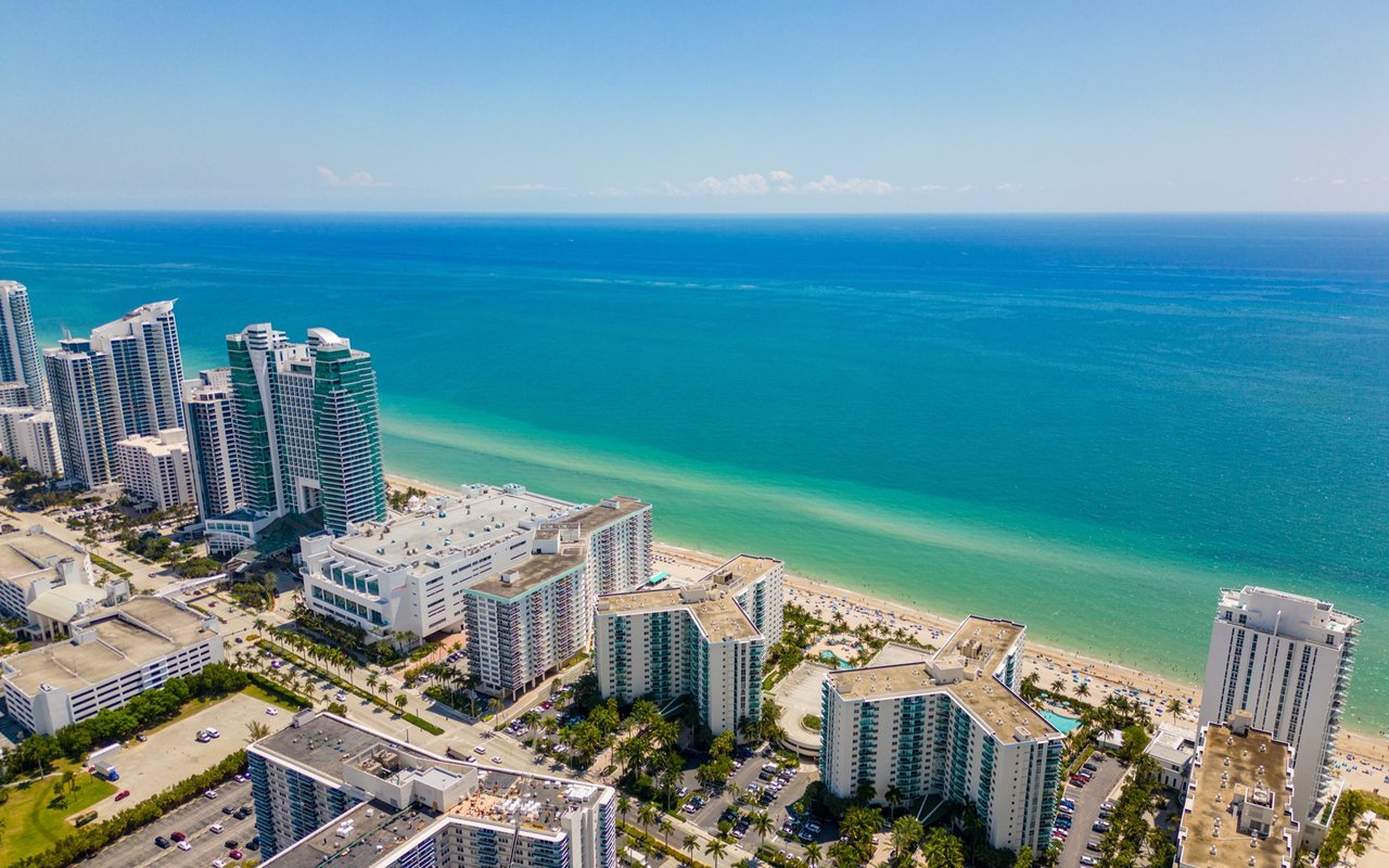 Beachfront high-rises beside turquoise ocean and sandy shoreline.