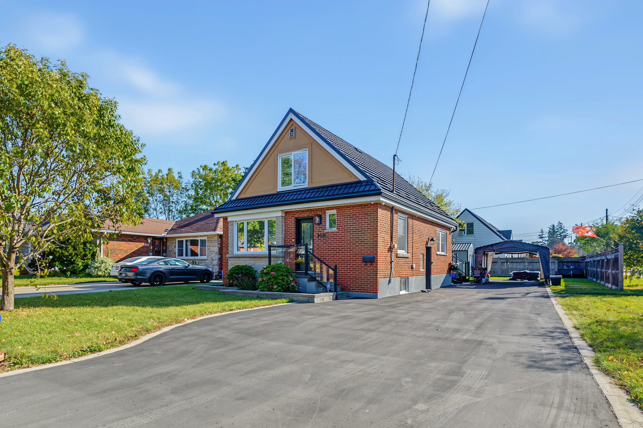 Red-brick house with a steep gabled roof and broad paved driveway.