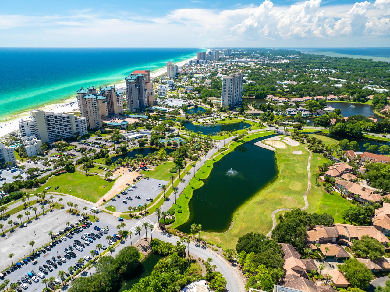 Wide aerial from the emerald Gulf shoreline across the Sandestin golf course to Choctawhatchee Bay in Miramar Beach, Florida