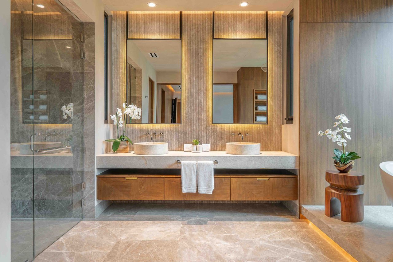 Luxury bathroom with a double vanity, stone shower, and orchids beside a freestanding tub.