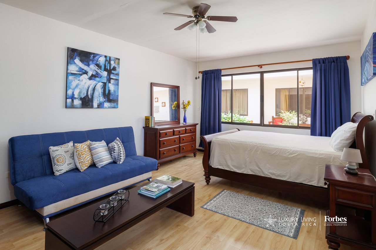 Furnished bedroom with a wooden bed, blue curtains, and a blue sofa seating area.