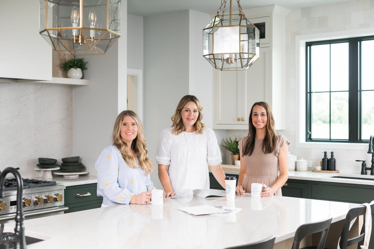 The Insiders Realty team standing in a modern Madison home kitchen, reviewing real estate data to determine if 2026 is a good time to sell a house in Madison, Wisconsin.