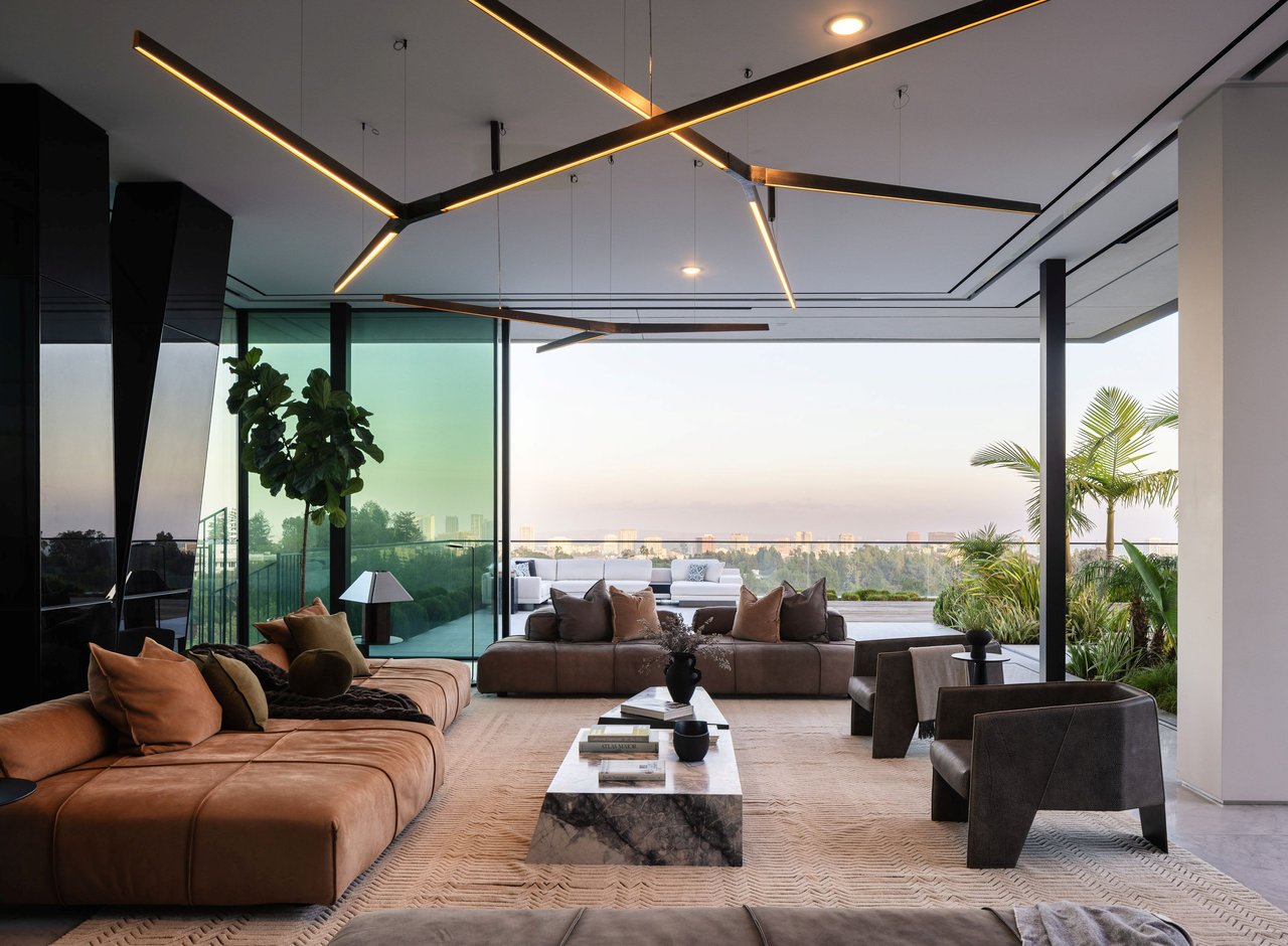 Modern living room with sculptural ceiling lights, floor-to-ceiling glass, and a Los Angeles skyline view.