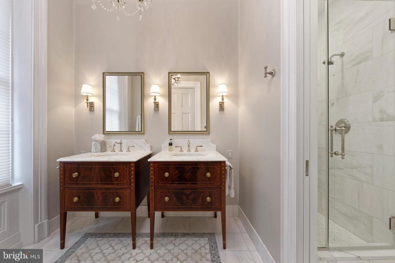 Bathroom with twin dark wood vanities and a marble-tiled glass shower.