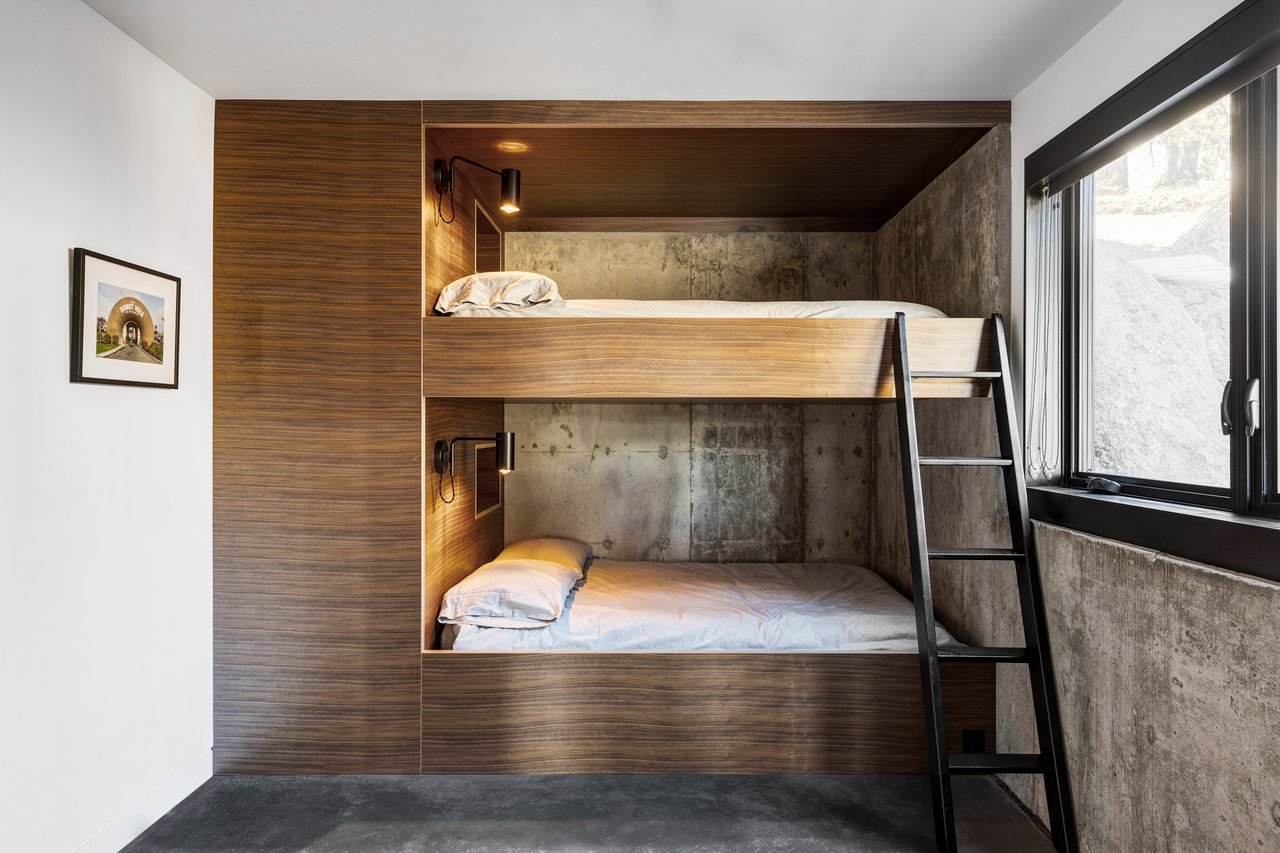 Modern built-in bunk beds with walnut paneling, concrete accents, and black metal ladder in Boulder mountain home