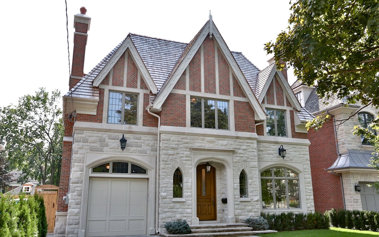 A three-story Tudor-style house with a brick facade and a stone base