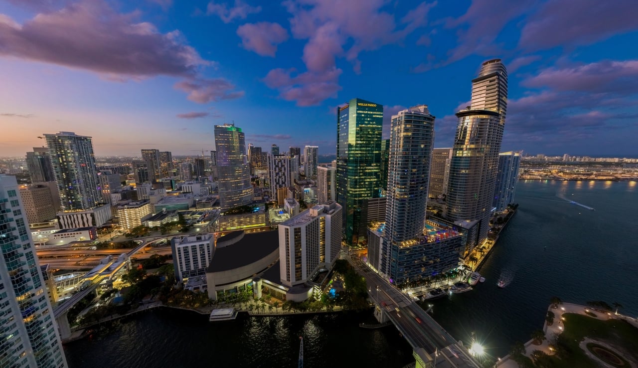Brickell skyline at dusk, with illuminated towers along the waterfront and Biscayne Bay.