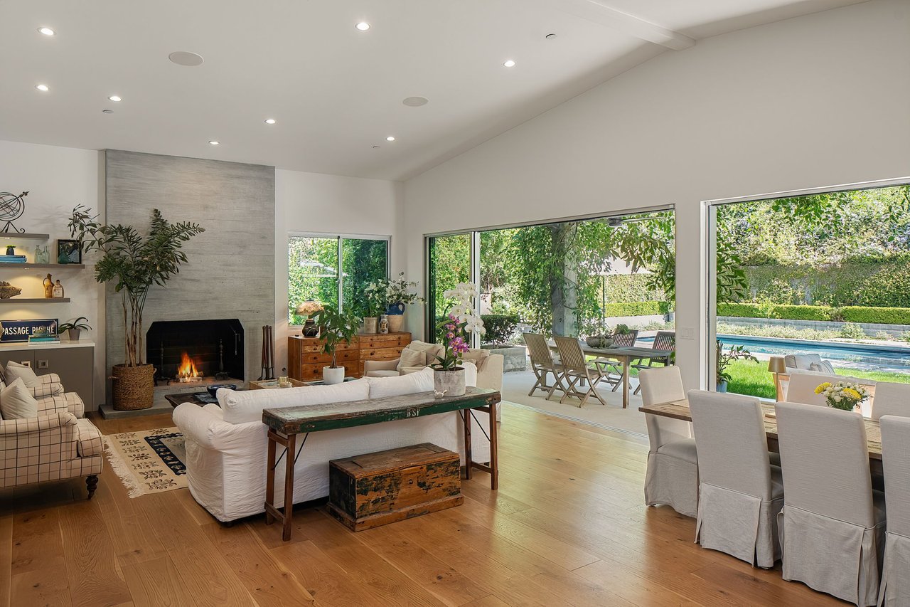 Living room with a fireplace and glass doors overlooking the garden and pool.