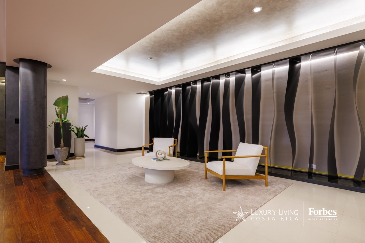 Modern lounge with white armchairs, a round coffee table, and a dramatic wave-patterned wall.