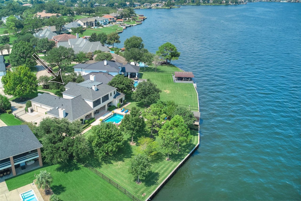 Aerial view of lakeside homes, with a white arrow pointing to one house.