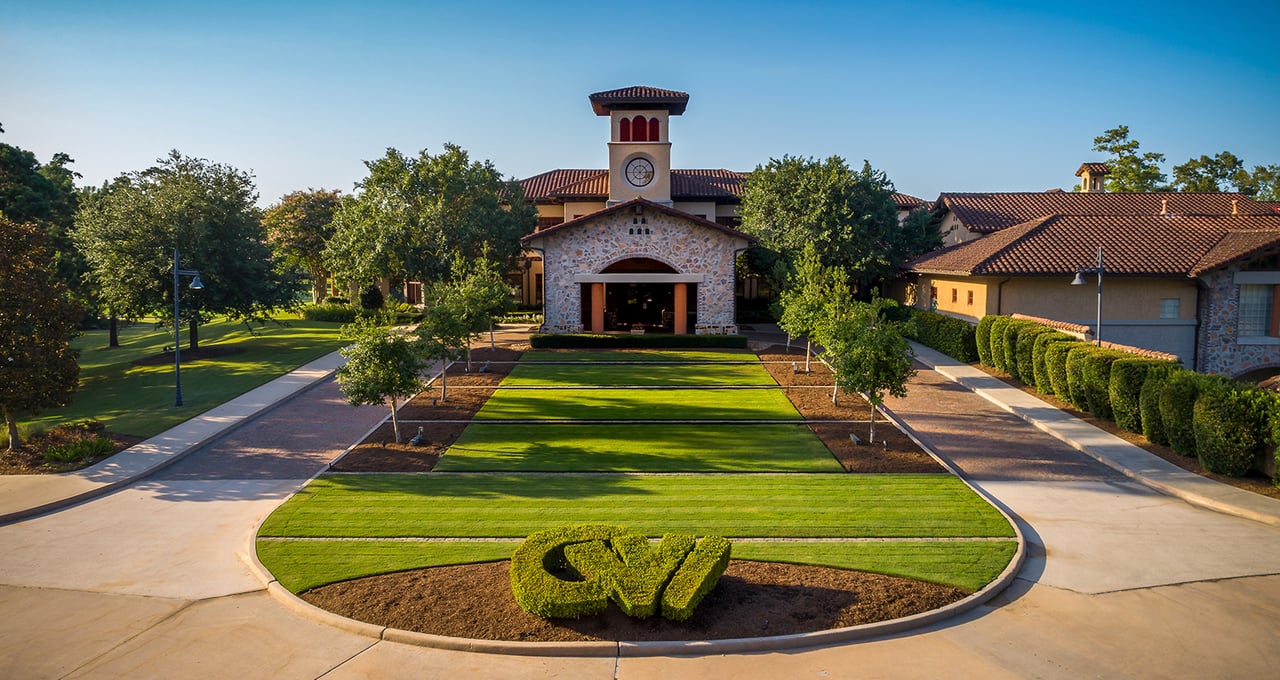 Carlton Woods clubhouse entrance with a landscaped circular lawn and stone façade.
