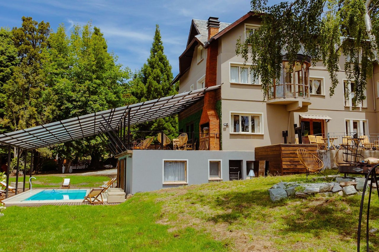 Boutique hotel exterior with a swimming pool, covered patio, and outdoor seating.