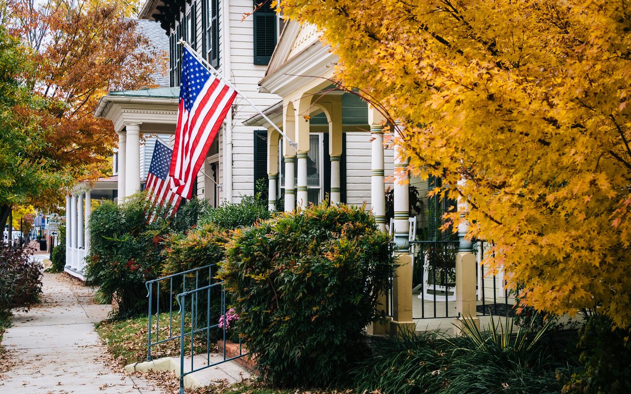 Bethesda homes with covered porches and American flags beneath autumn foliage.