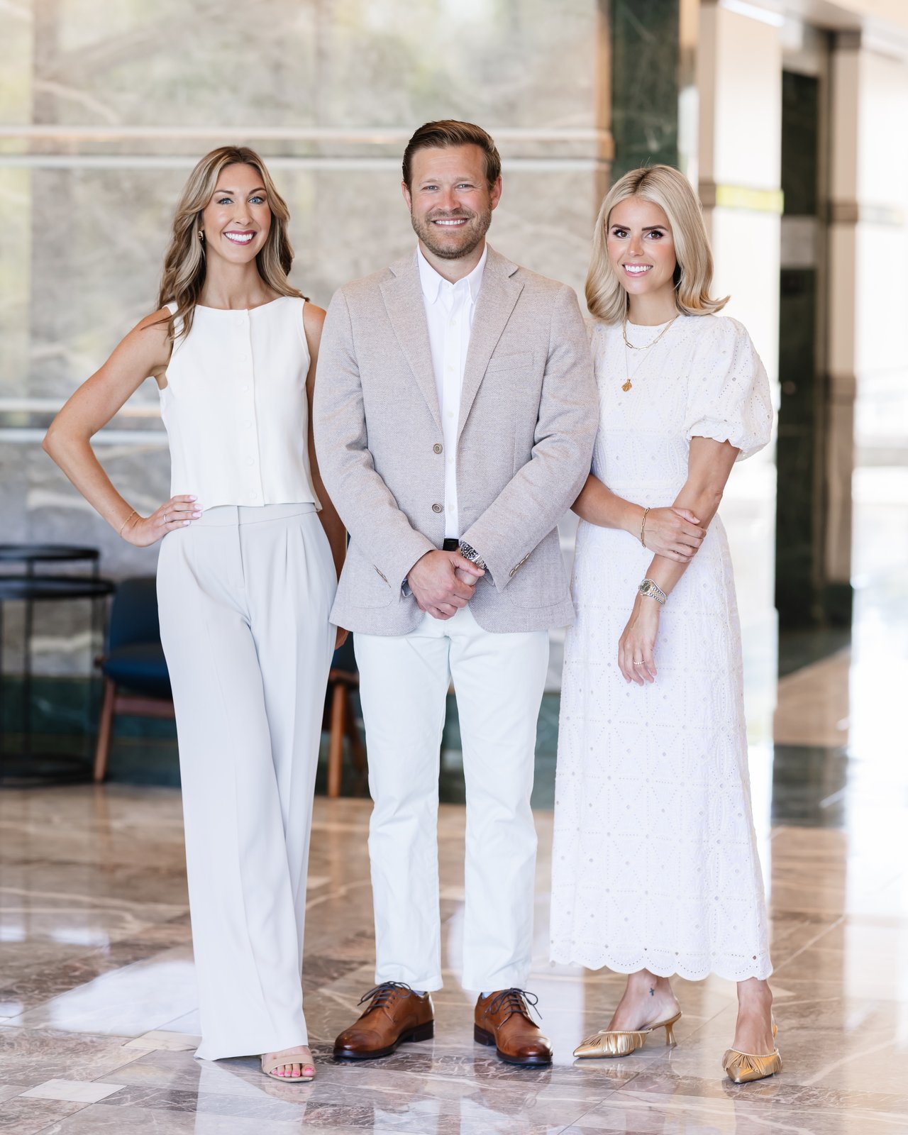Clymer & Co. Realty Group, three agents posing together in a bright marble lobby.