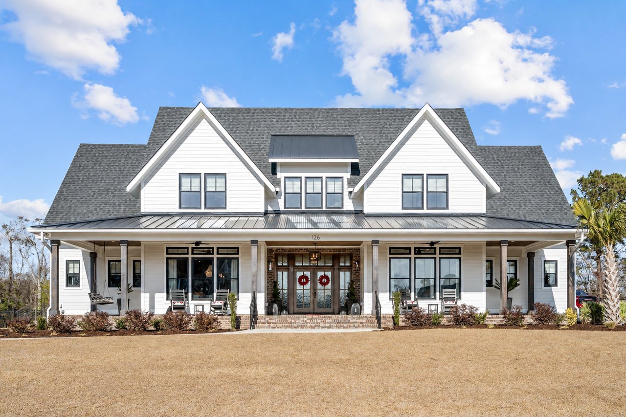 White two-story house with twin gables, a wide covered porch, and a brick entry.