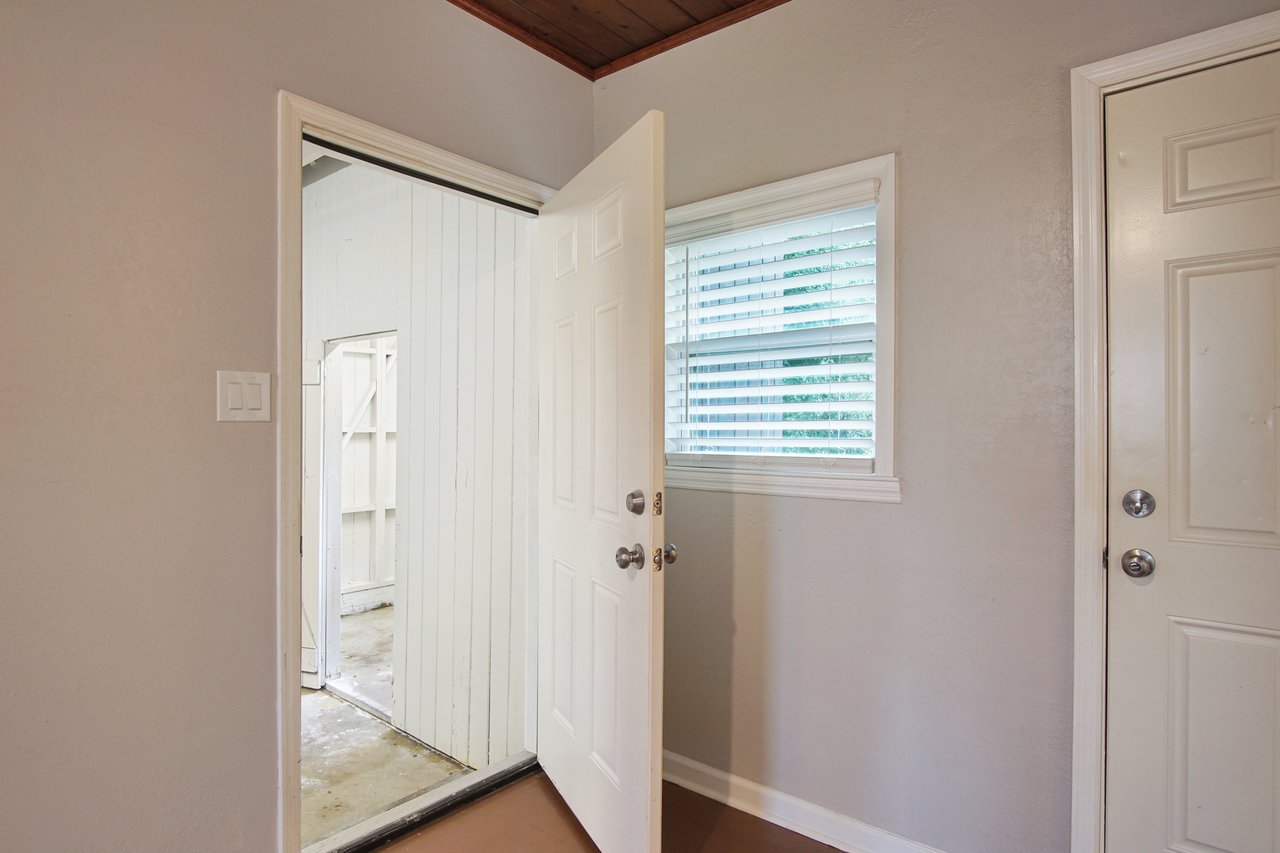 An open white door reveals a glimpse into a well-lit room, inviting exploration and curiosity.