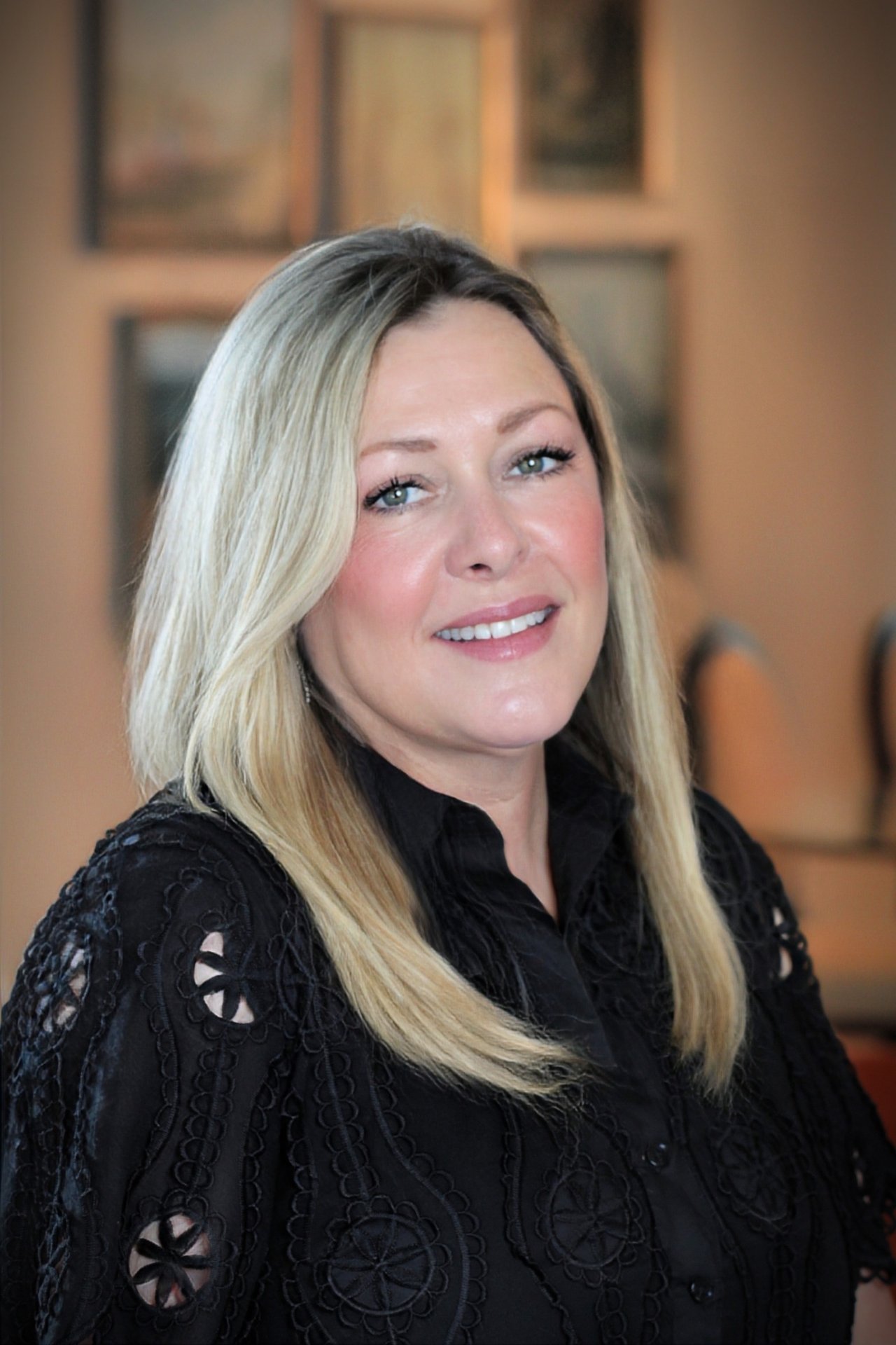 Cindy Coberth, smiling with long blonde hair and wearing a black embroidered blouse.
