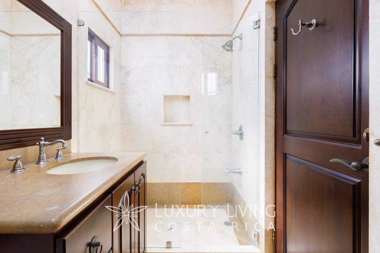 Bathroom with a stone vanity, dark wood cabinetry, and glass-enclosed shower.
