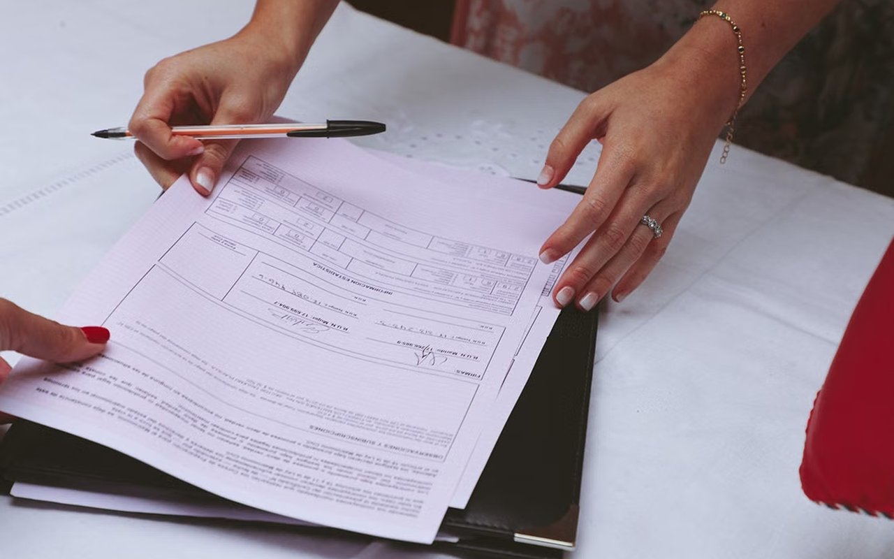 People review and sign a real estate contract on a black portfolio.