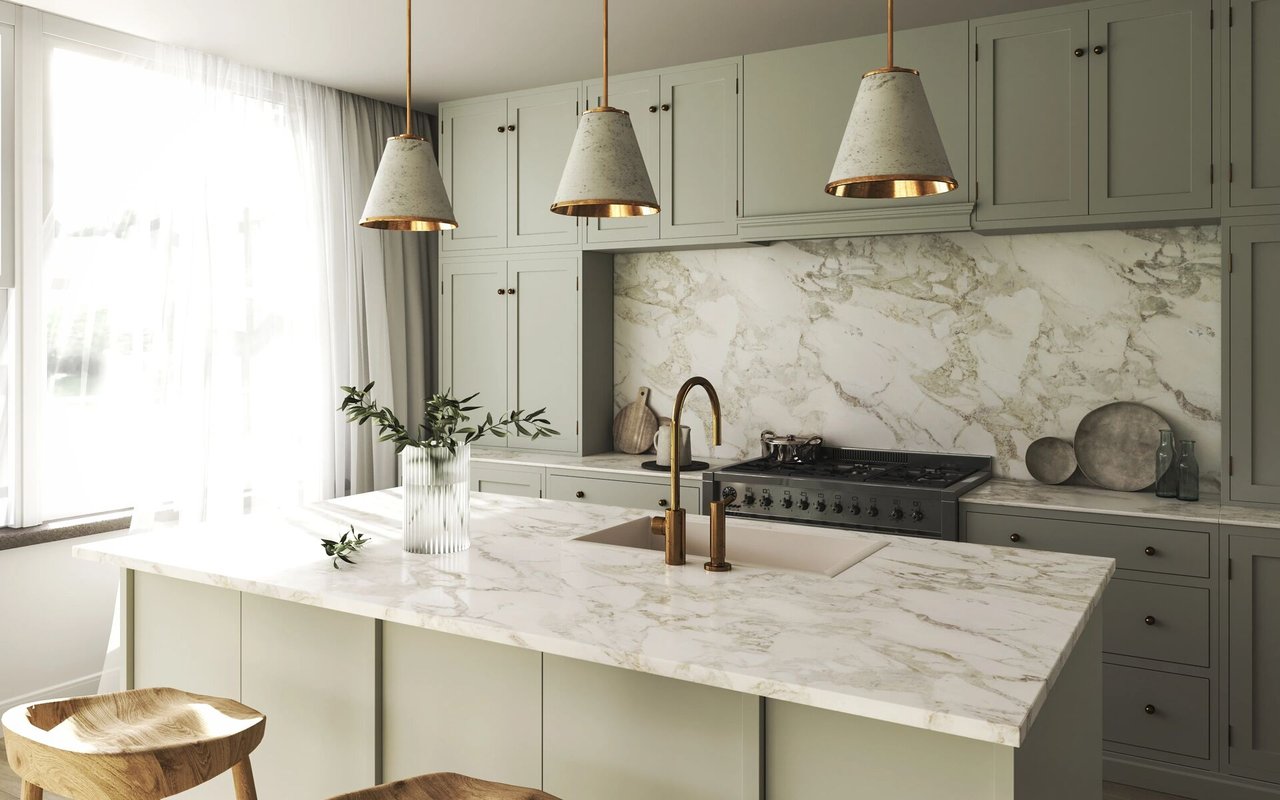 Bright kitchen with a marble island, brass faucet, pale cabinets, and three pendant lights.