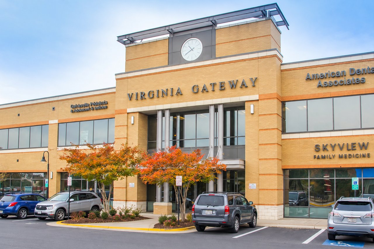 Virginia Gateway building with a central clock tower, medical office signs, and autumn trees.