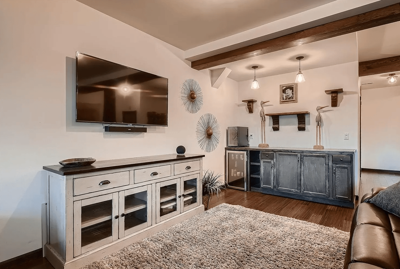 Living room with a built-in wet bar, exposed wood beams, and wall-mounted television.