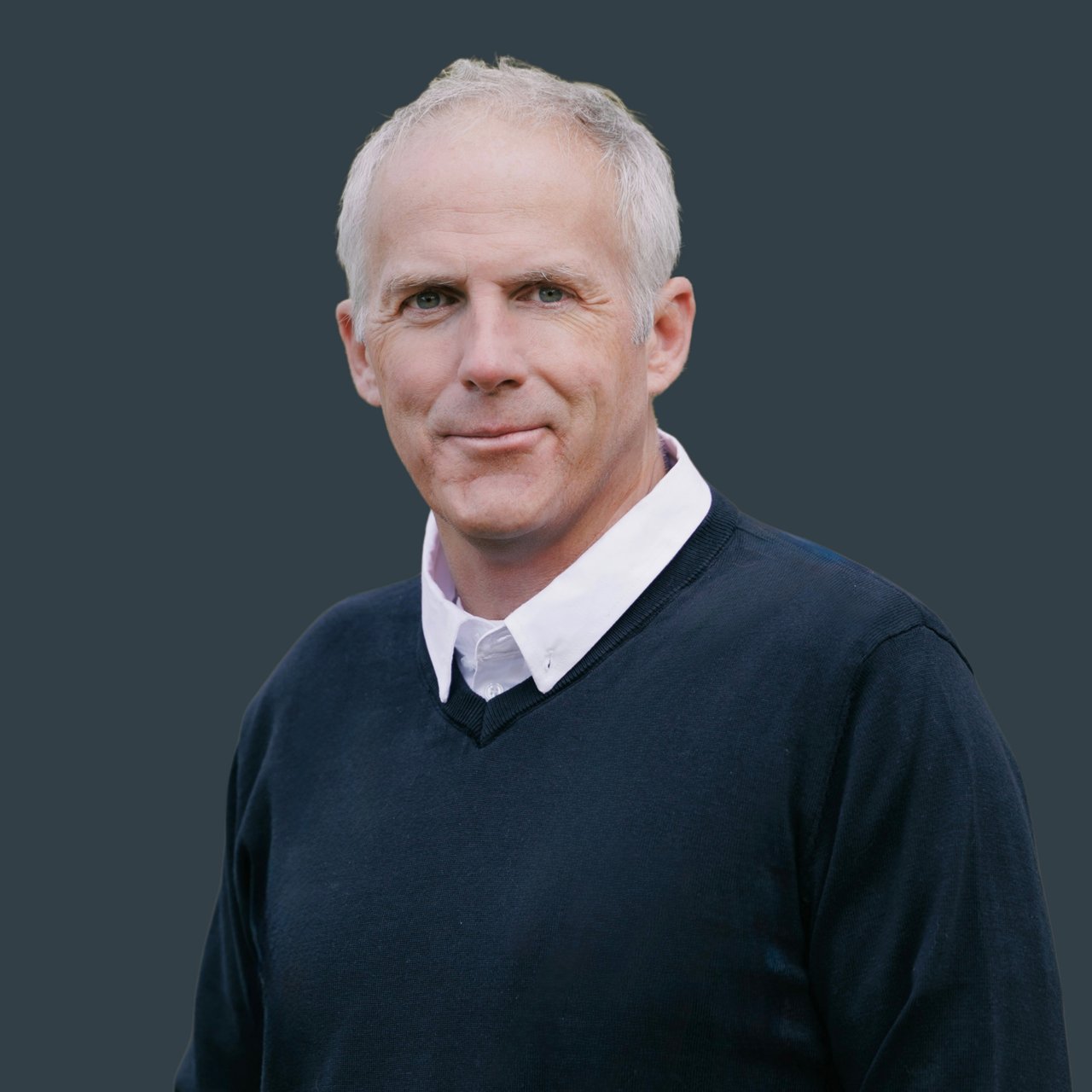 Chris Dolan, Denver real estate agent, professional headshot with blue background.