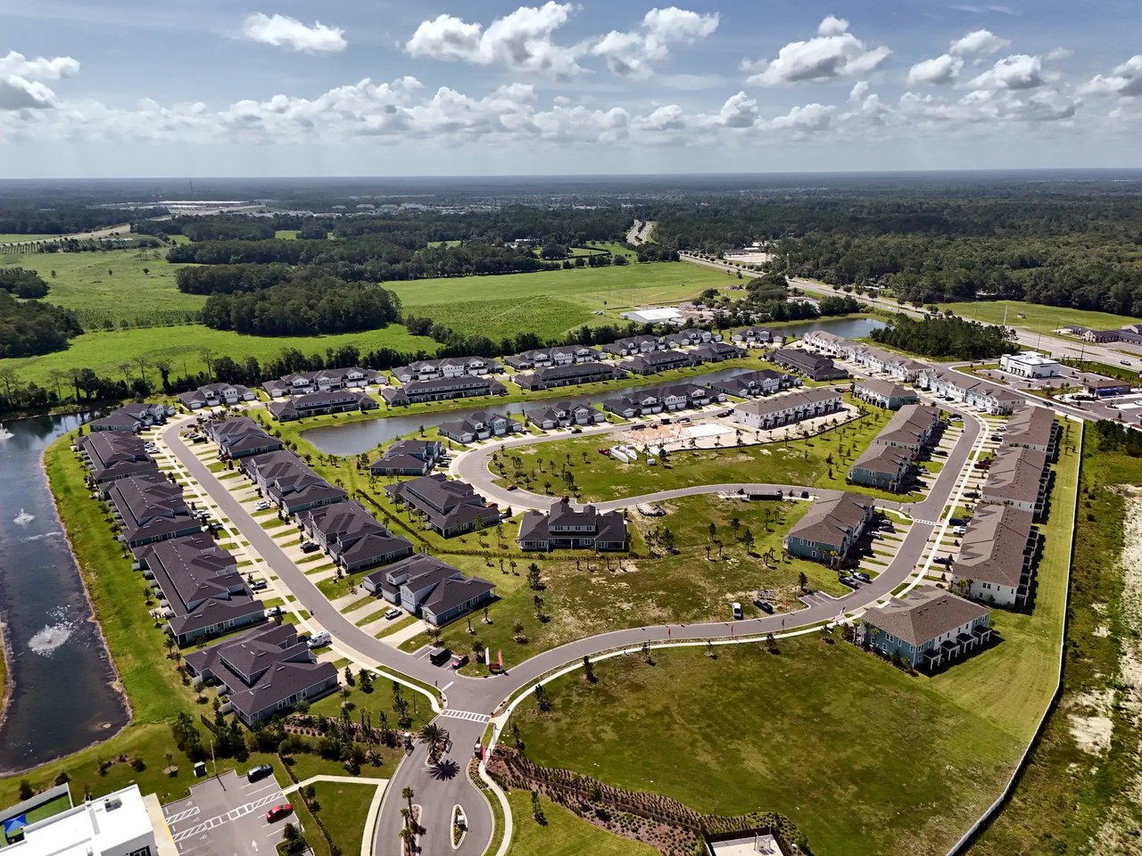 Aerial view of a residential community with curving streets, ponds, and homes under construction.