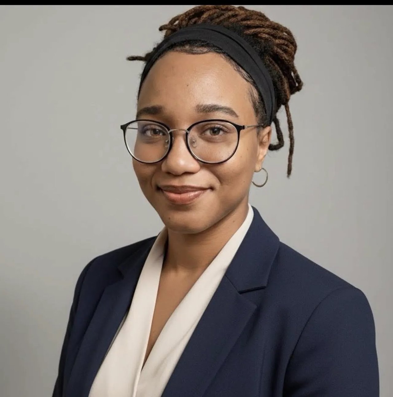 Tavinia Semedo wearing round glasses and a navy blazer.