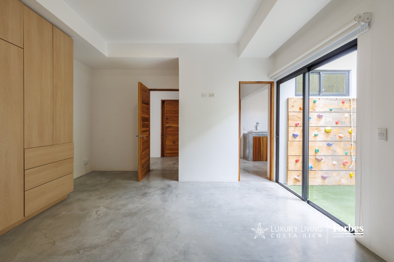 Bedroom with built-in wood wardrobes, concrete floor, and sliding doors to an outdoor climbing wall.
