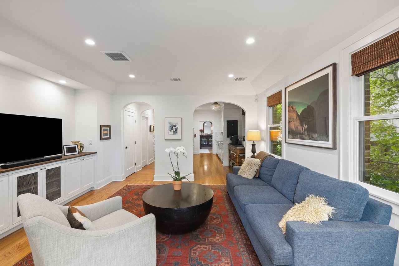 Living room with a blue sectional, round coffee table, patterned rug, and arched openings.