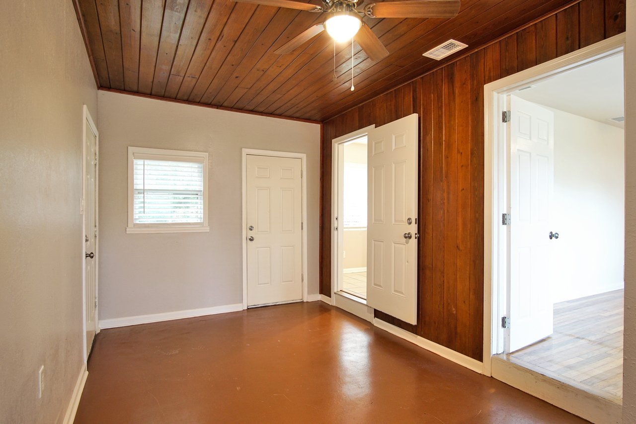 A hallway featuring wood paneling, and a ceiling fan