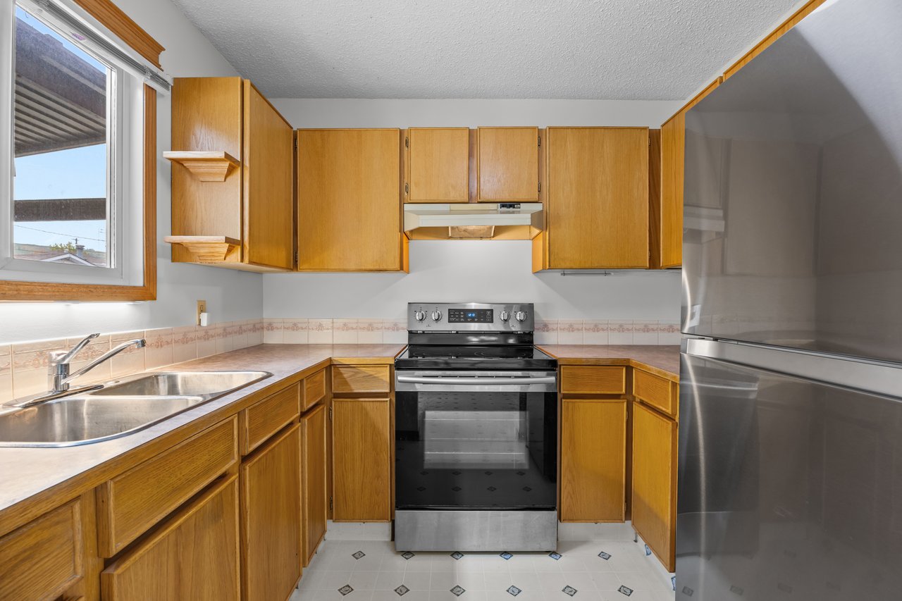 Kitchen with honey-colored wood cabinets, a double sink, and stainless-steel appliances.
