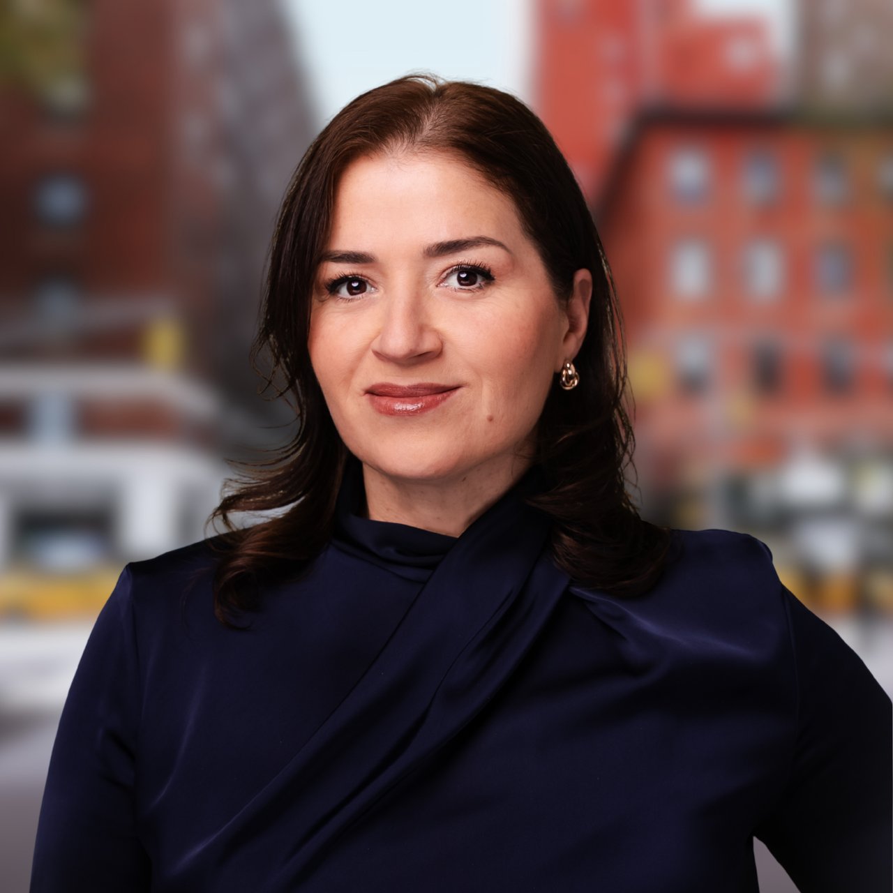 Shkurte Gashi in a navy blouse against a blurred urban backdrop.